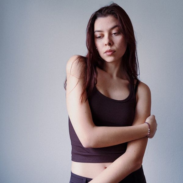Person in a peaceful stretching pose against a minimalist backdrop.
